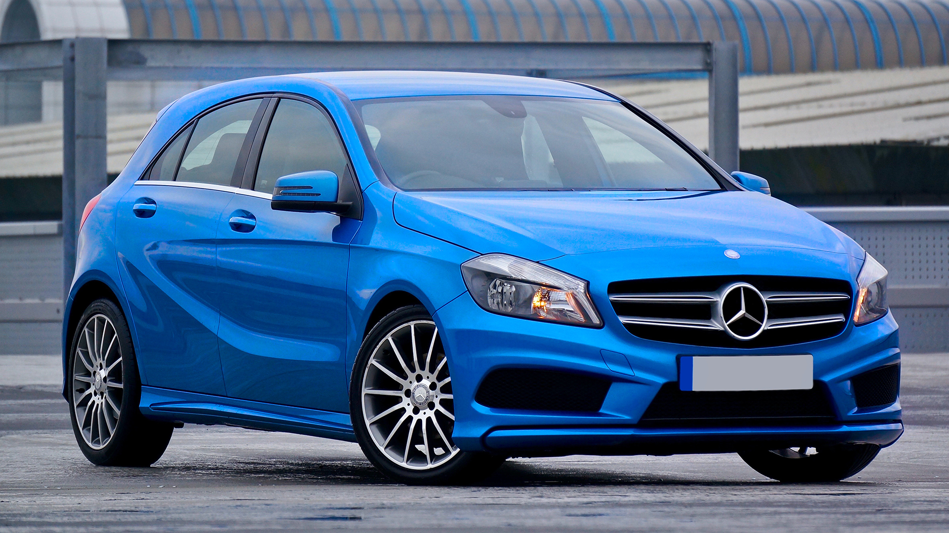 A blue Mercedes-Benz A-Class is parked in front of a building.